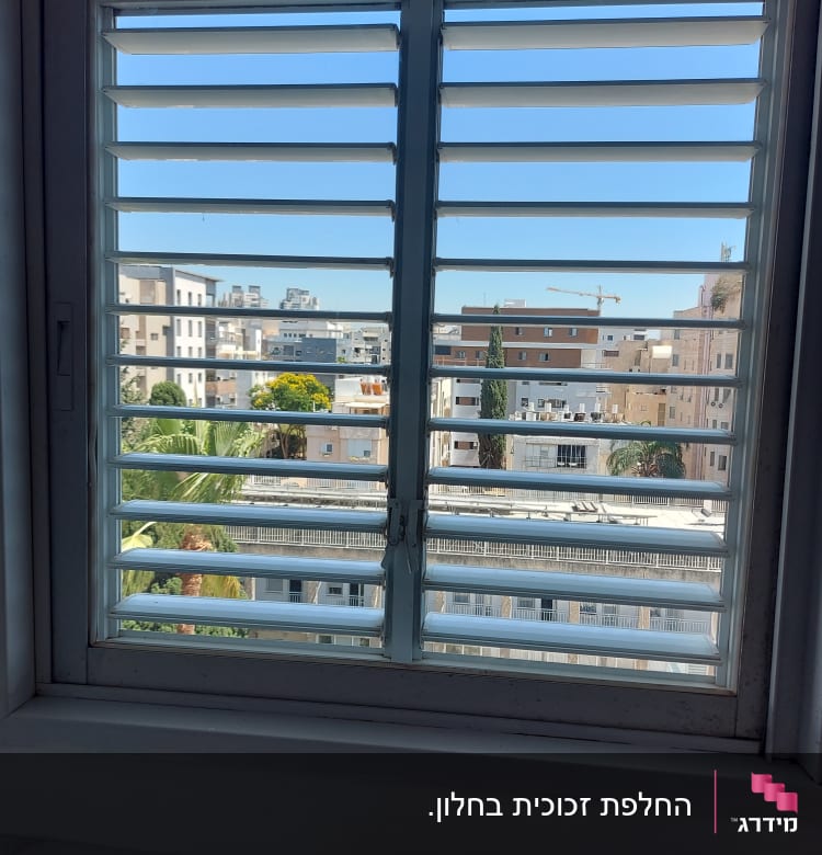 חלון זכוכית עם תריסים פתוחים חלקית